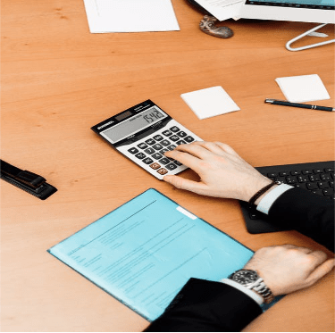 Person Using Calculator on Brown Wooden Surface.