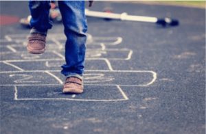 Kid playing hopscotch on playground outdoors.