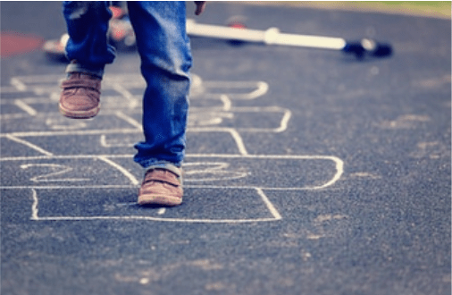 Kid playing hopscotch on playground outdoors.